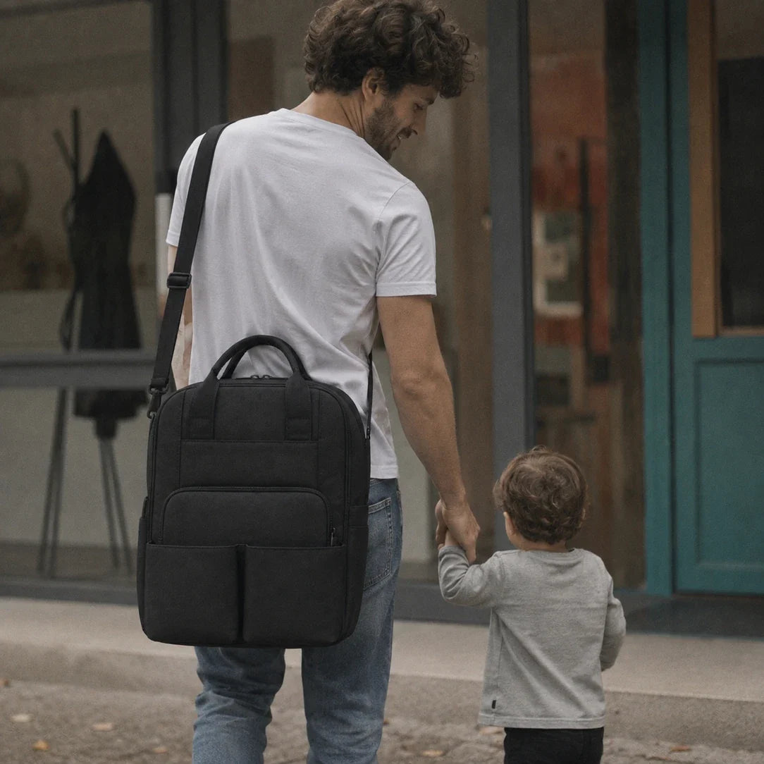 Sac à dos à langer compartimenté noir porté en sortie longue, bretelles incurvées et compartiment sec-humide Image