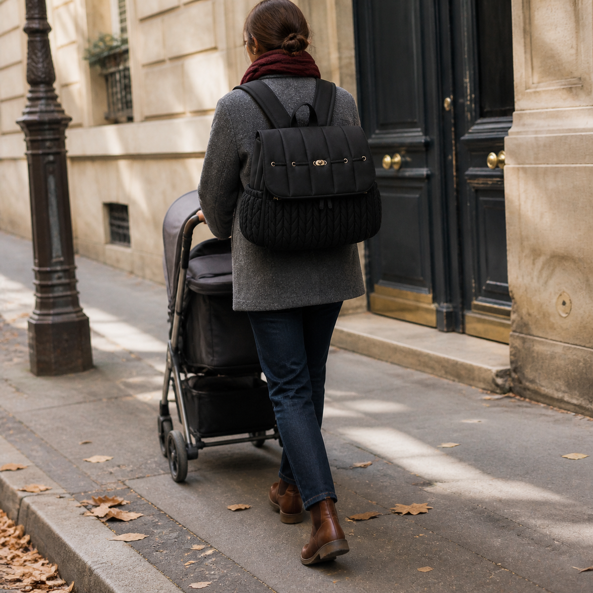 Sac à dos à langer tressé noir porté en ville avec une poussette | NOLIERA