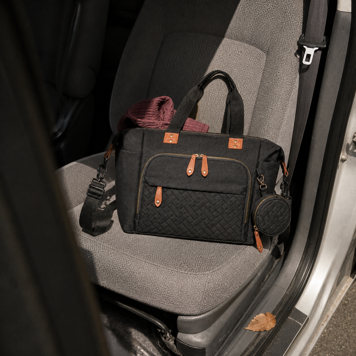 Sac à langer bandoulière noir posé sur un siège passager | NOLIERA