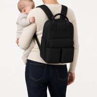Sac à dos à langer noir porté avec un bébé dans les bras | NOLIERA