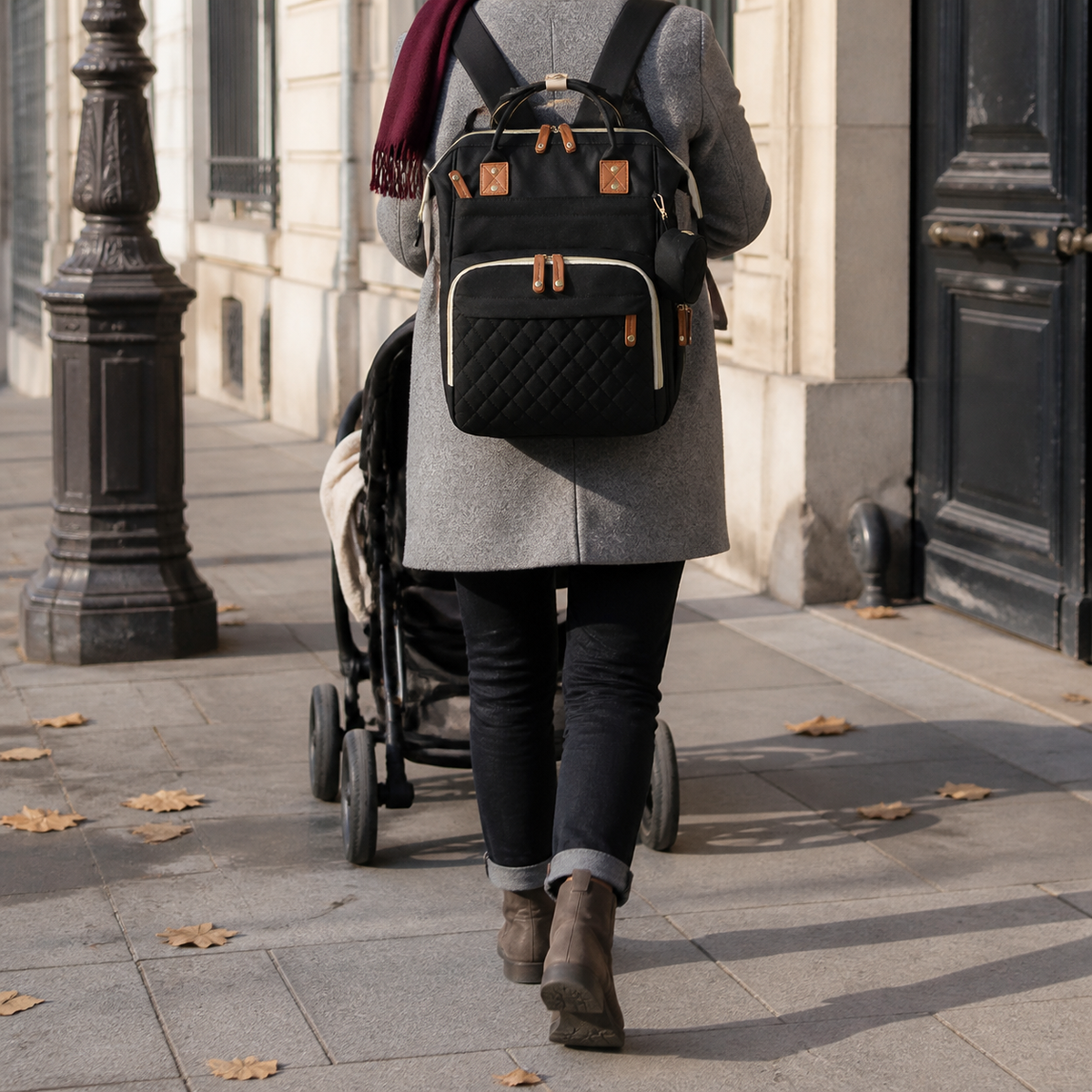 Sac à dos à langer noir porté en ville avec une poussette | NOLIERA