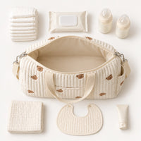 Affaires pour une journée avec bébé à côté du sac de maternité Ourson